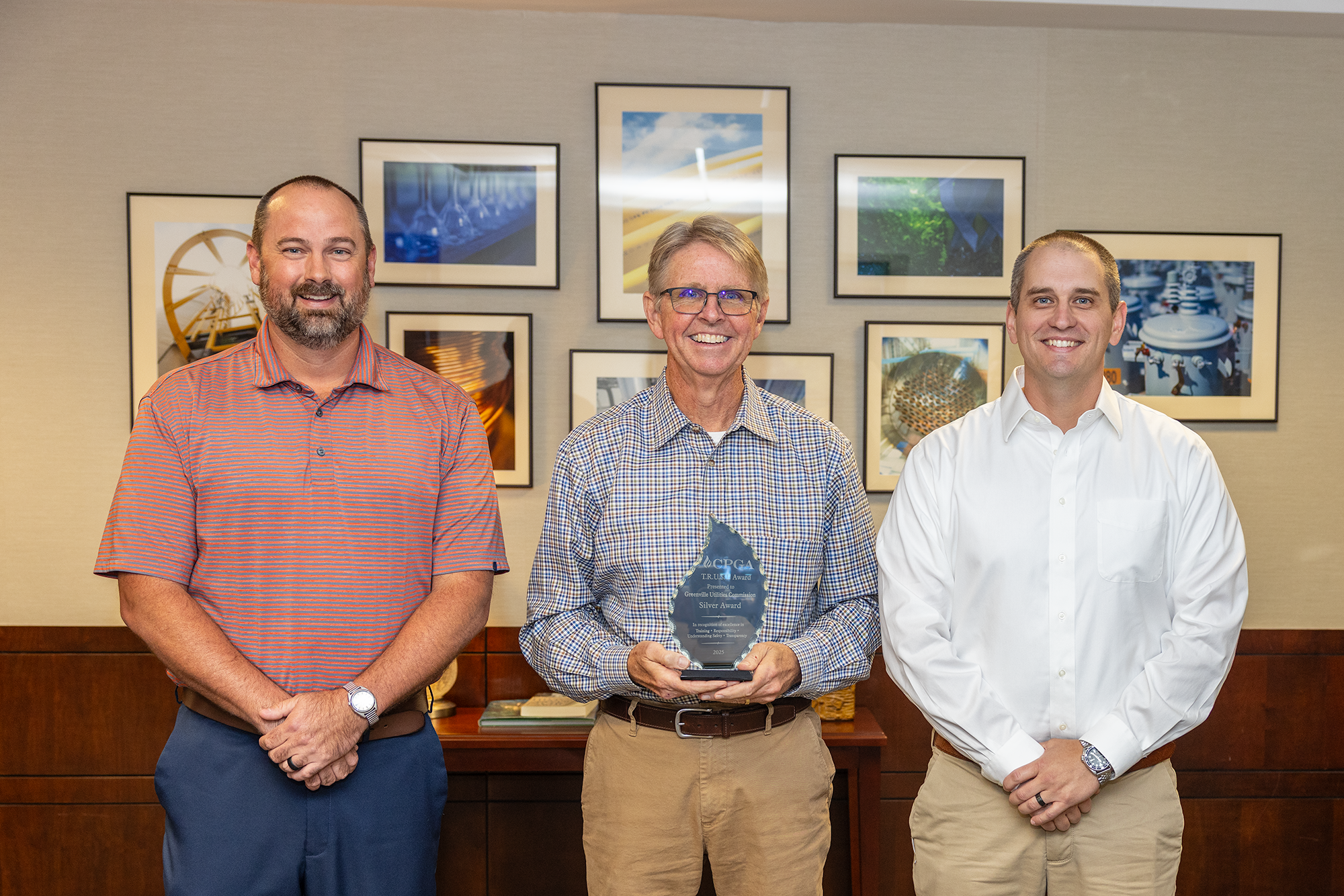 three men pose with award