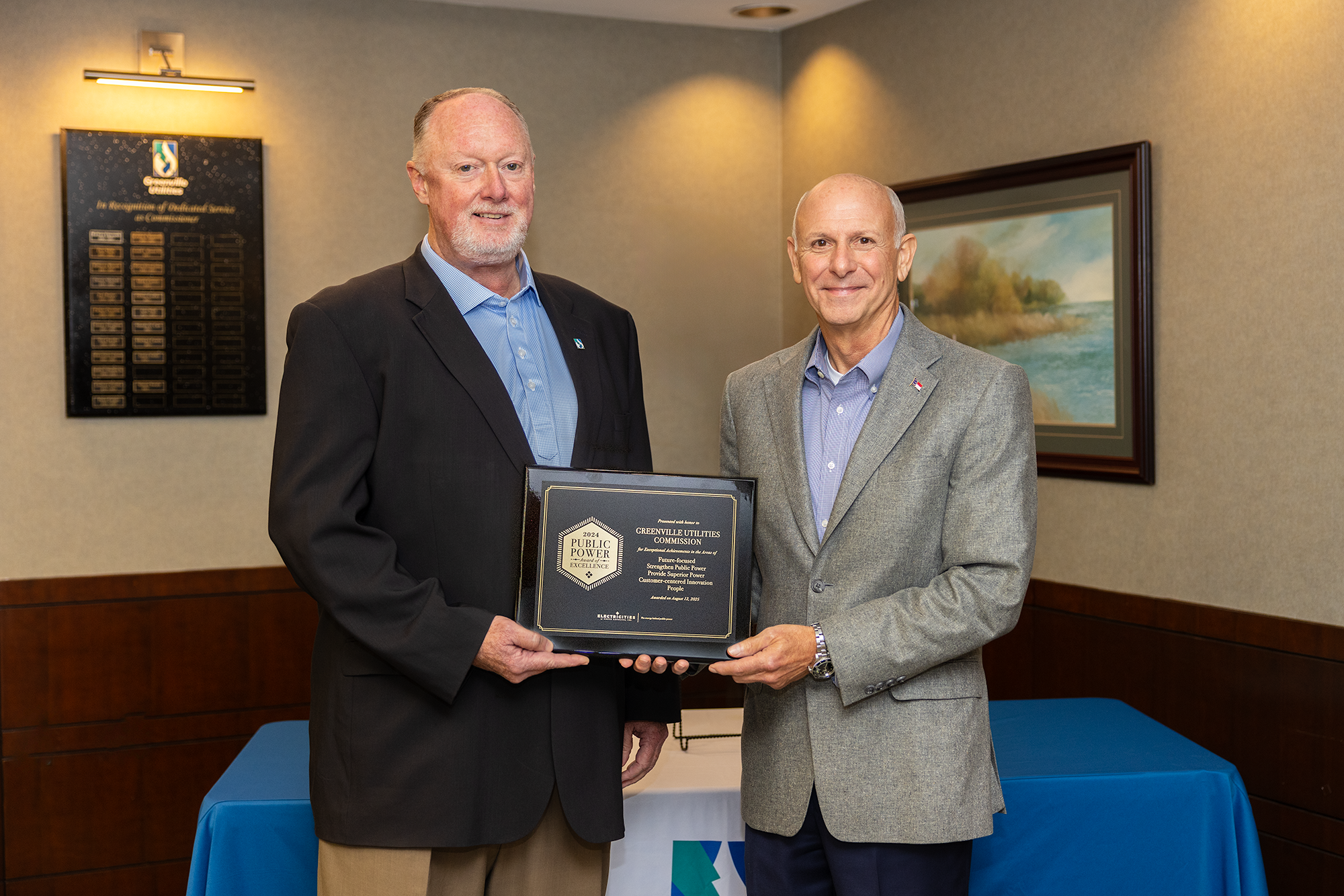 Two men hold award