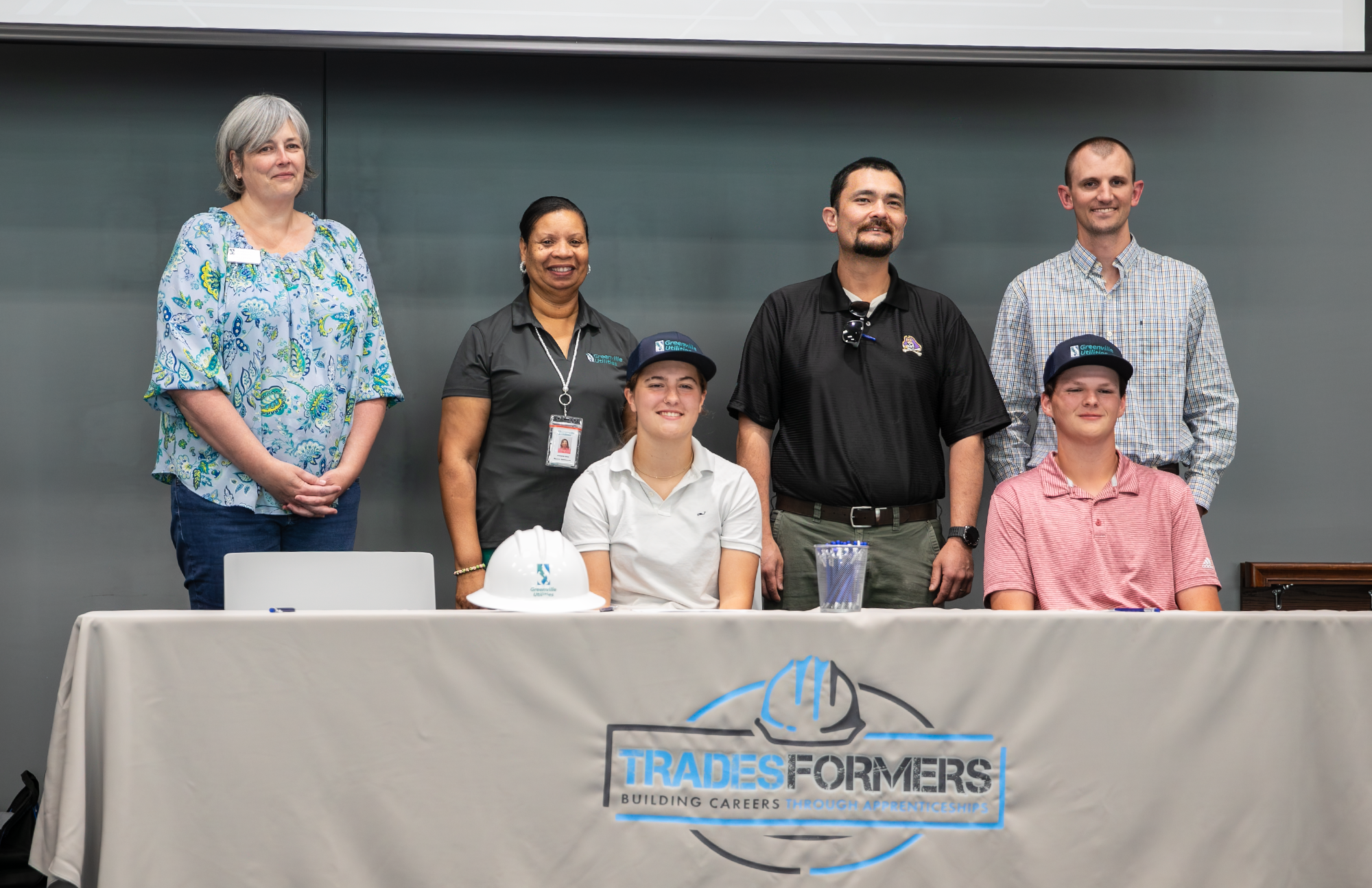 Four GUC employees stand while two new Tradesformers sit