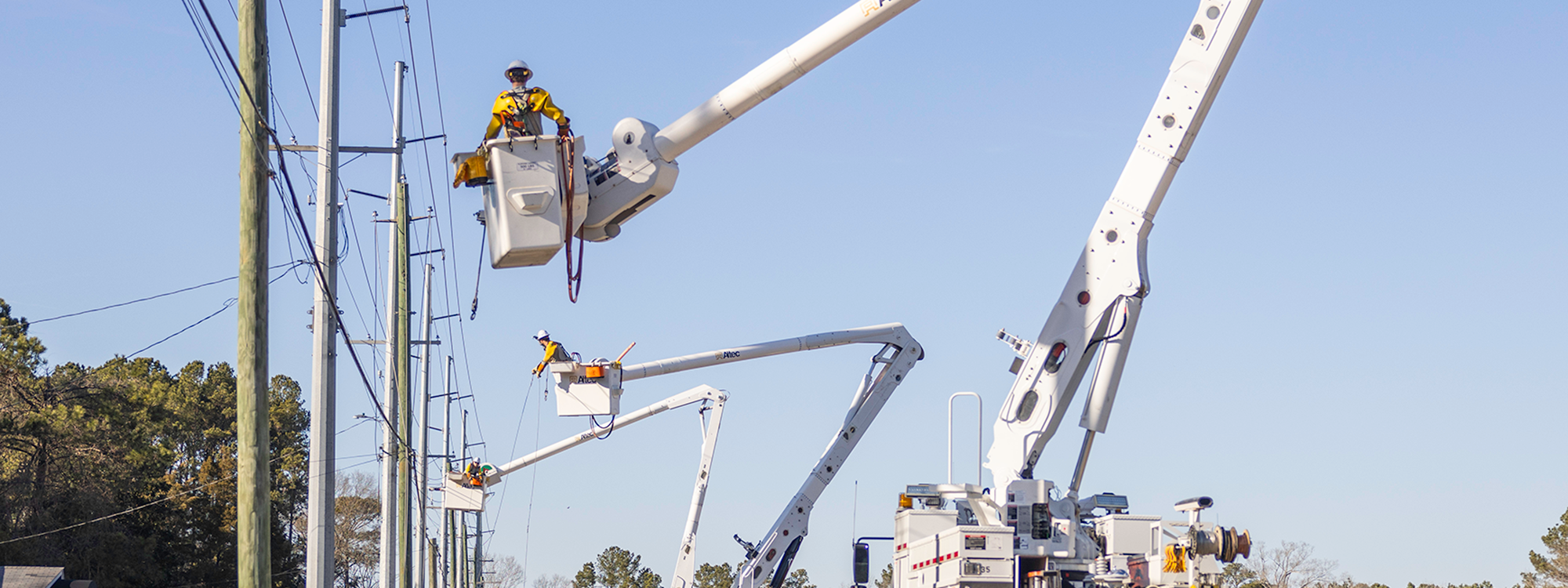 electric crews in bucket trucks along road