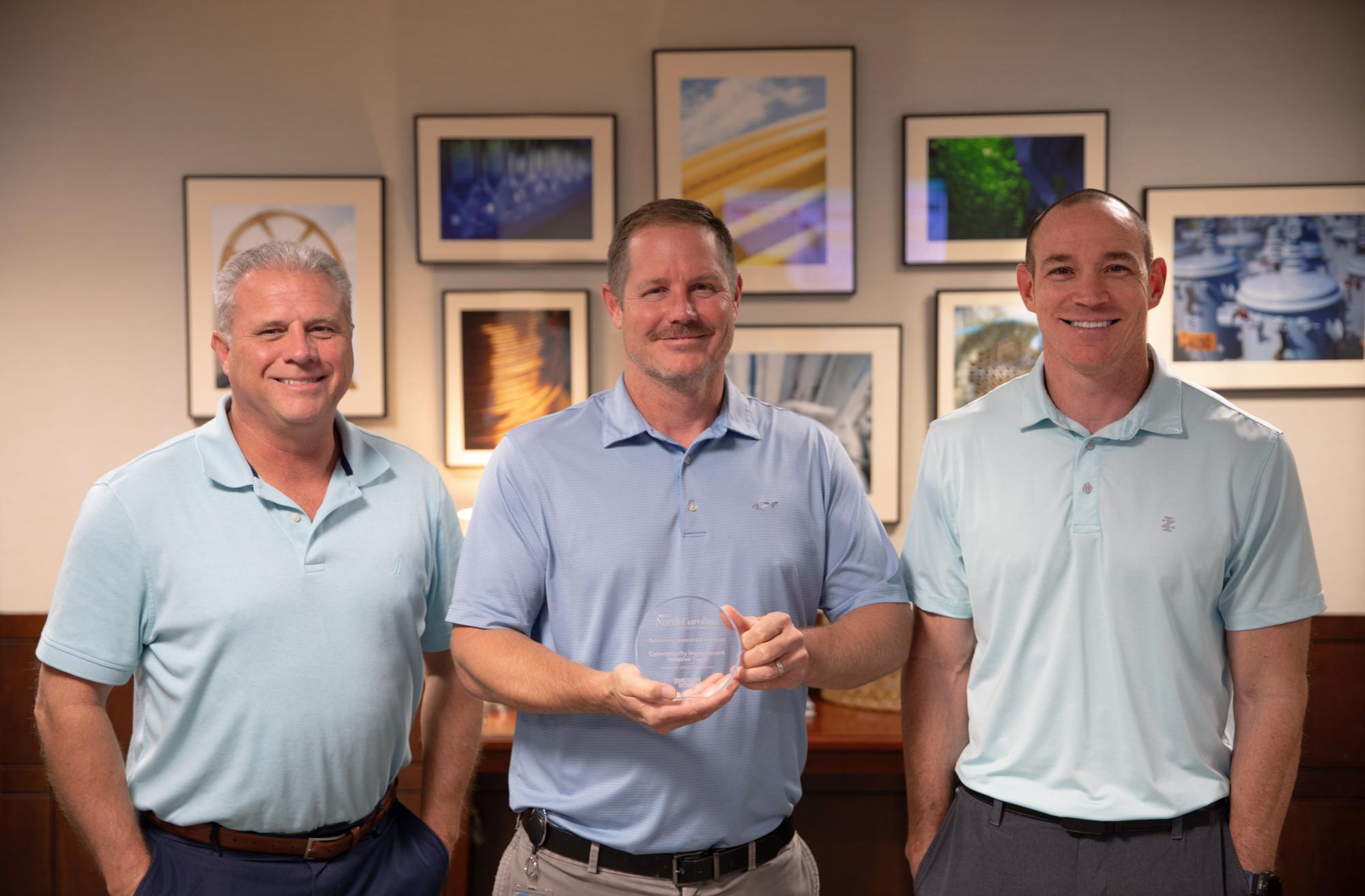Three men hold award